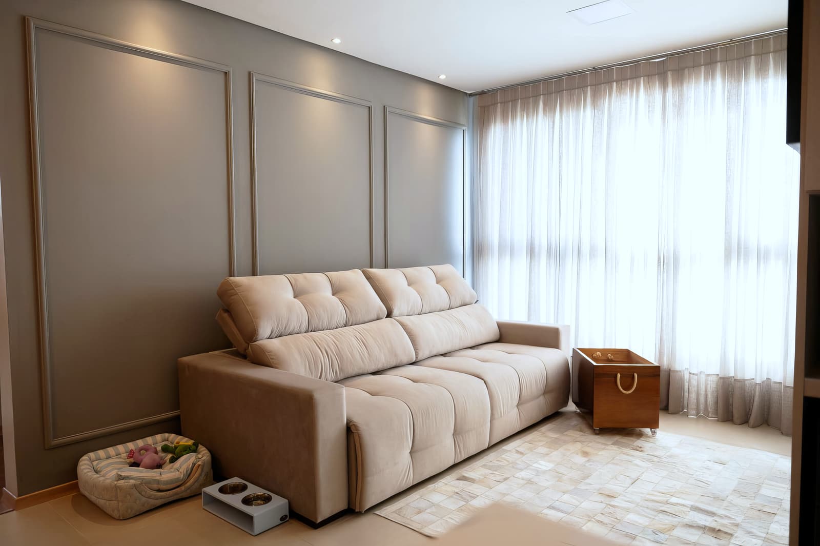 Sala de estar com sofá claro, boiserie e cortina de linho