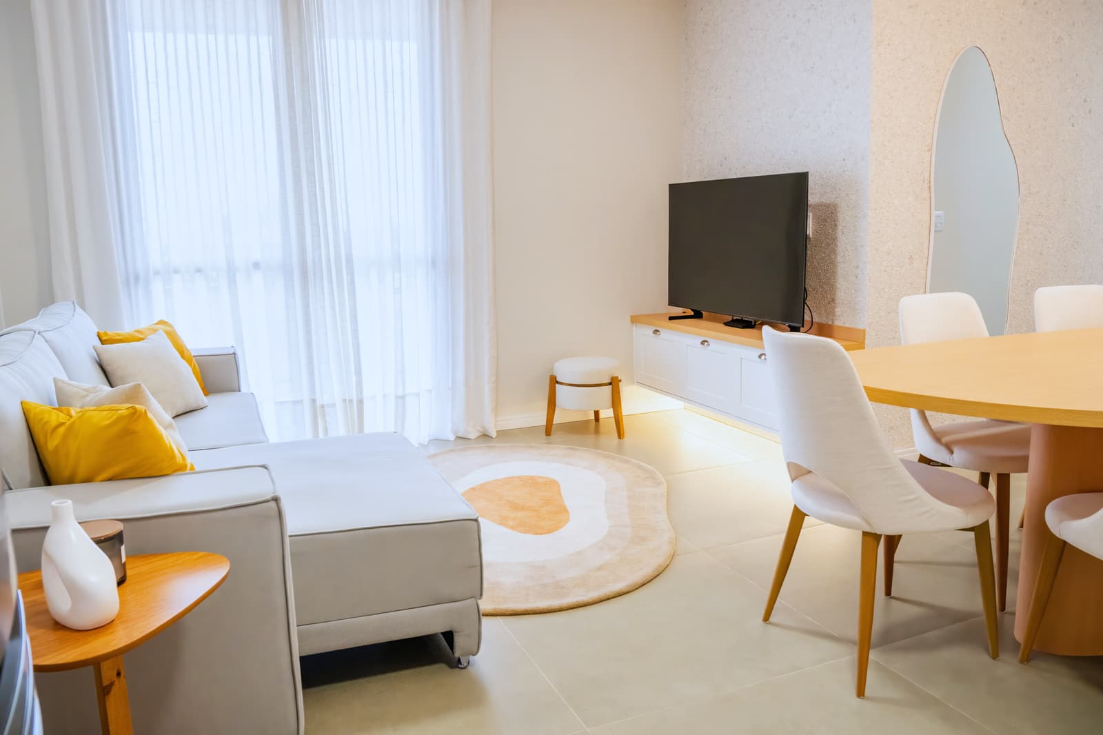 Sala de estar com cortina de luz difusa, sofá claro e almofada mostarda