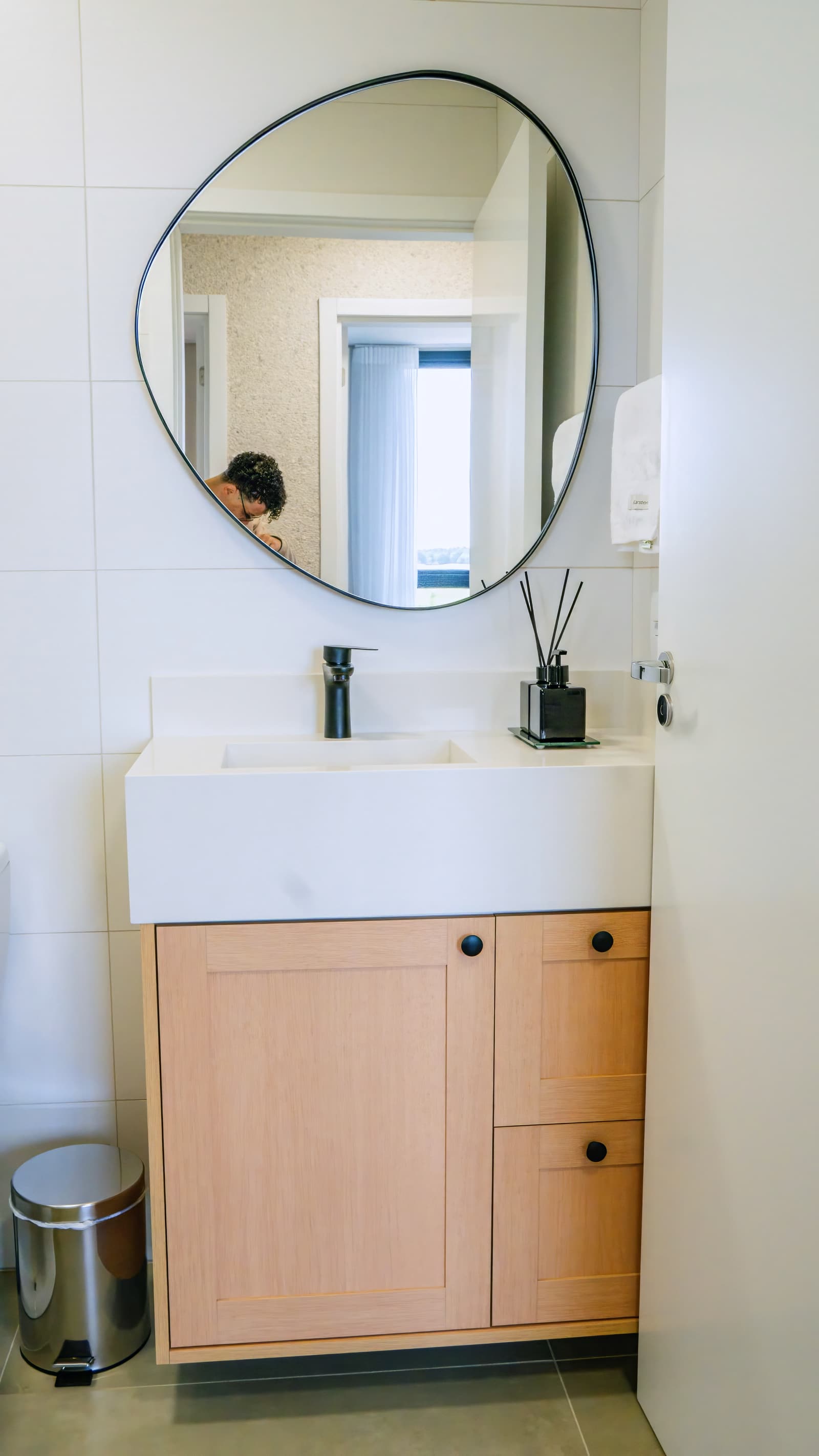 Lavabo com cuba esculpida, espelho redondo e metais pretos