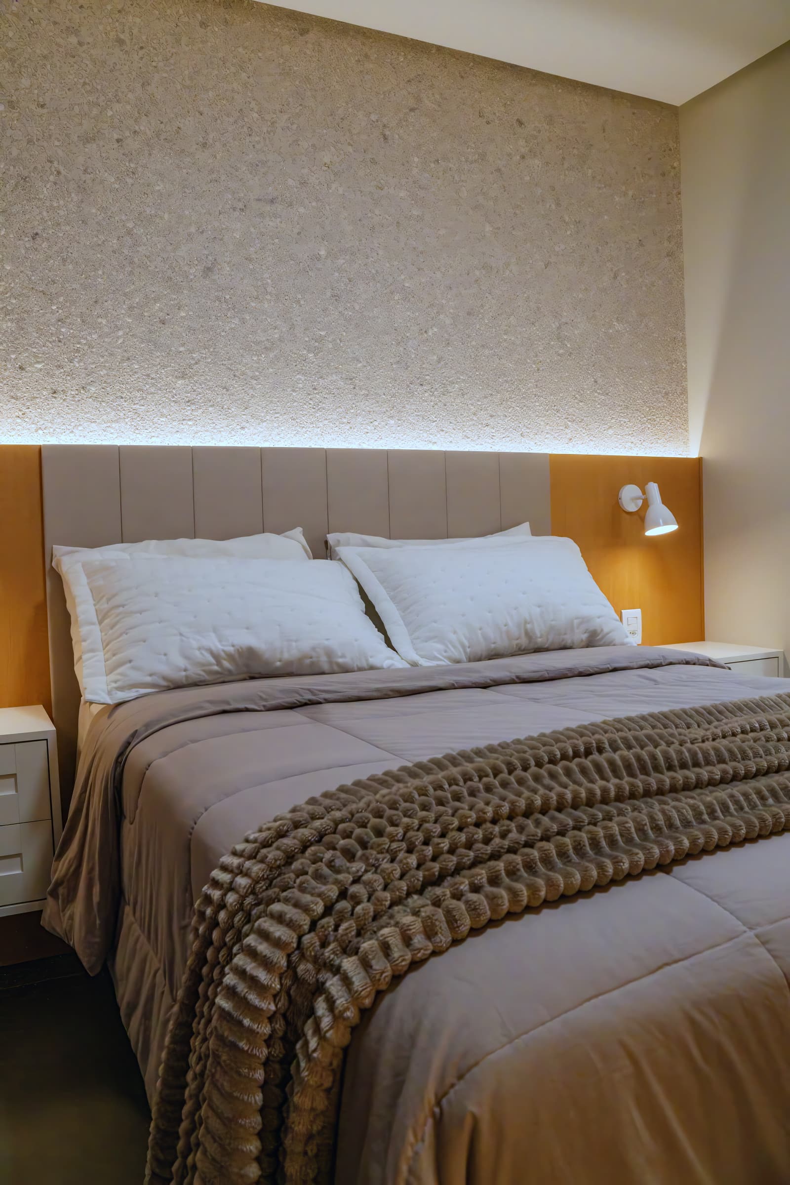 Quarto de casal com cabeceira estofada e iluminação embutida no forro