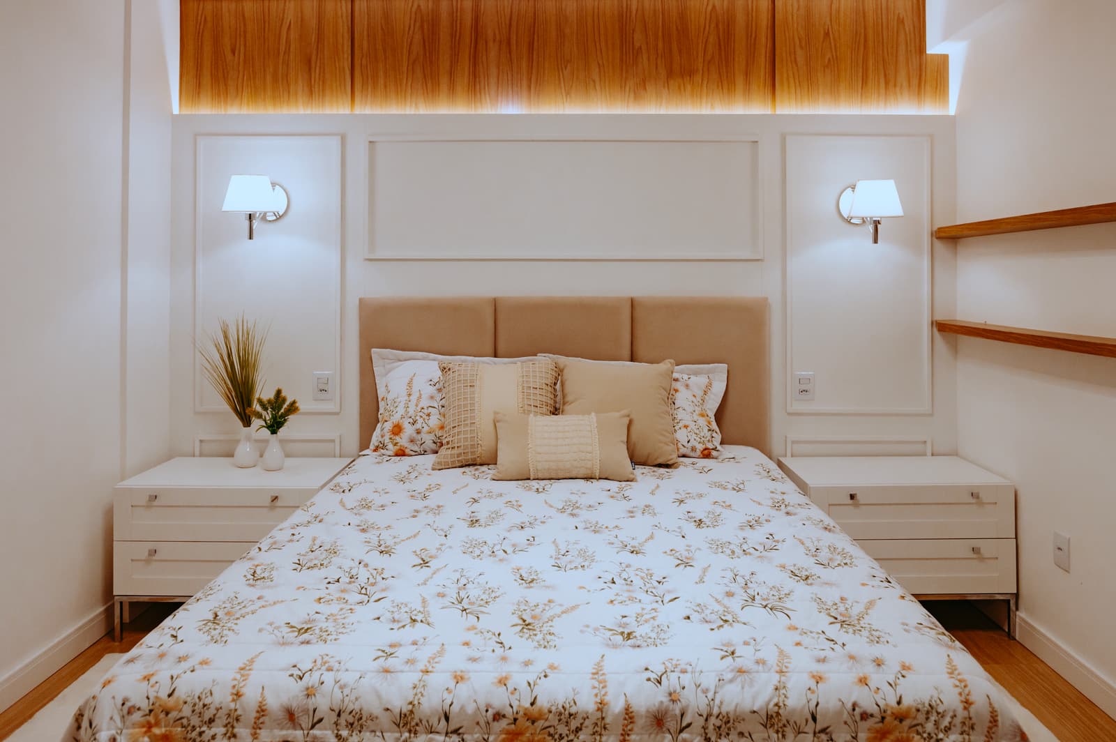 Quarto de casal com cabeceira estofada, arandelas e marcenaria clara