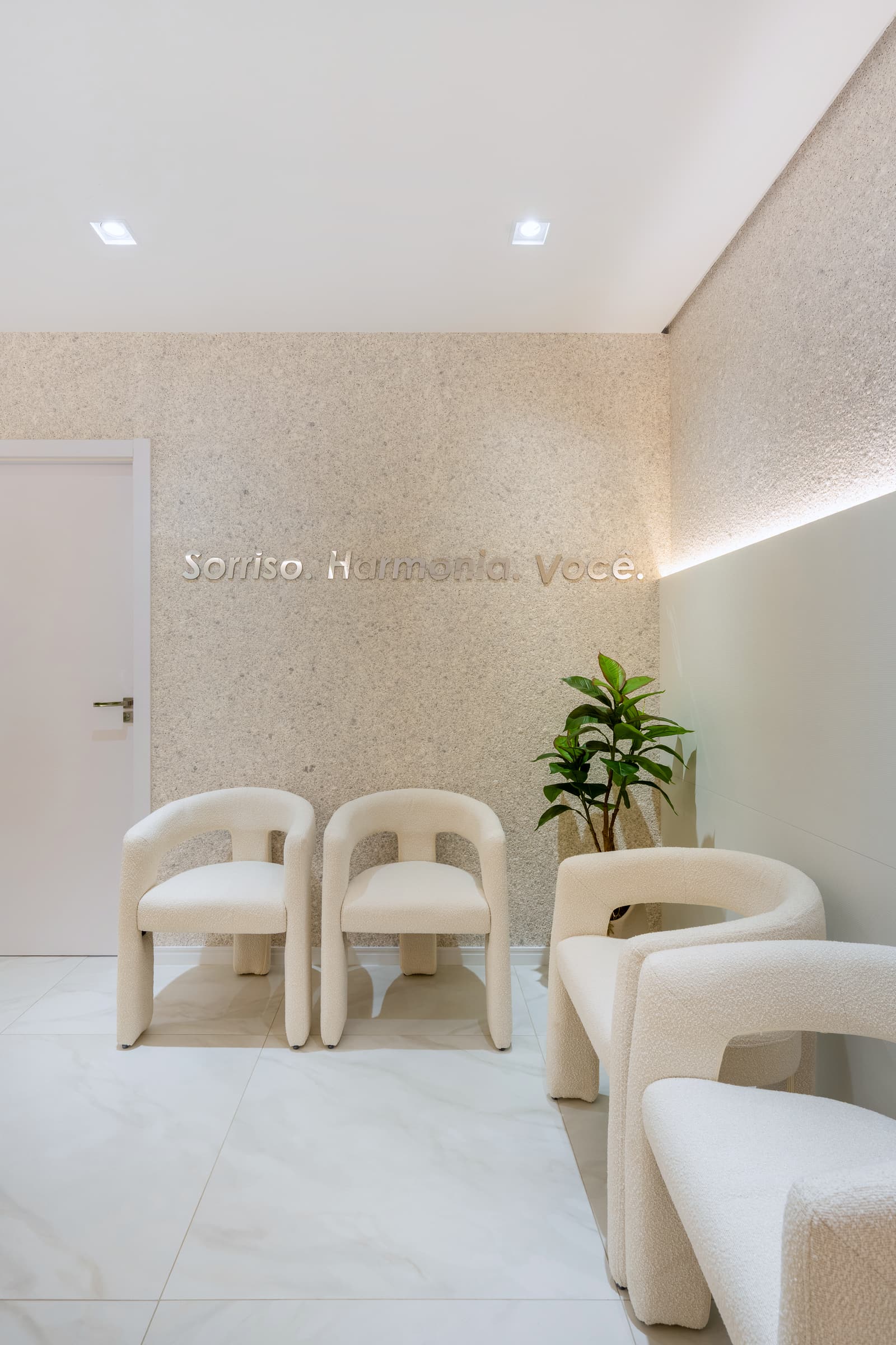 Sala de espera com poltronas claras de encosto curvo