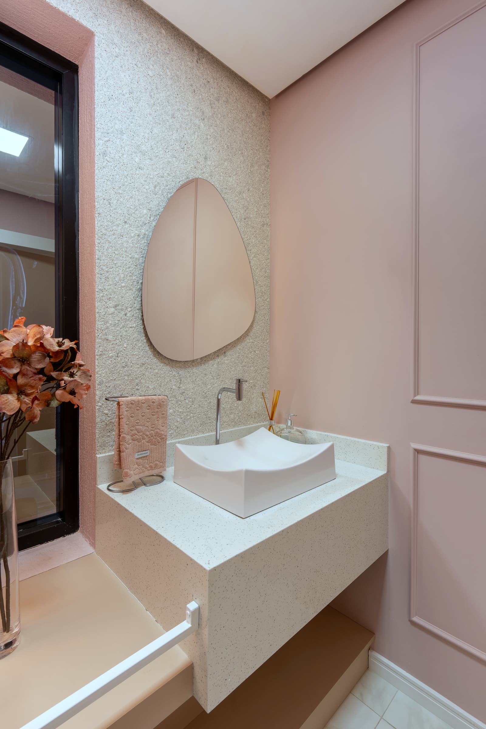 Lavabo com parede rosa em boiserie, cuba esculpida e espelho orgânico