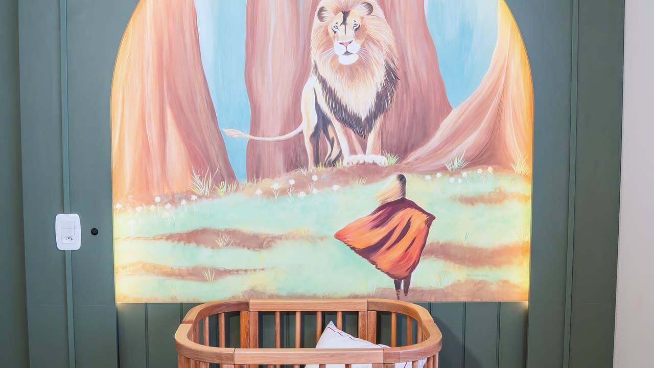 Quarto de bebê com mural pintado à mão, berço oval de madeira e marcenaria verde