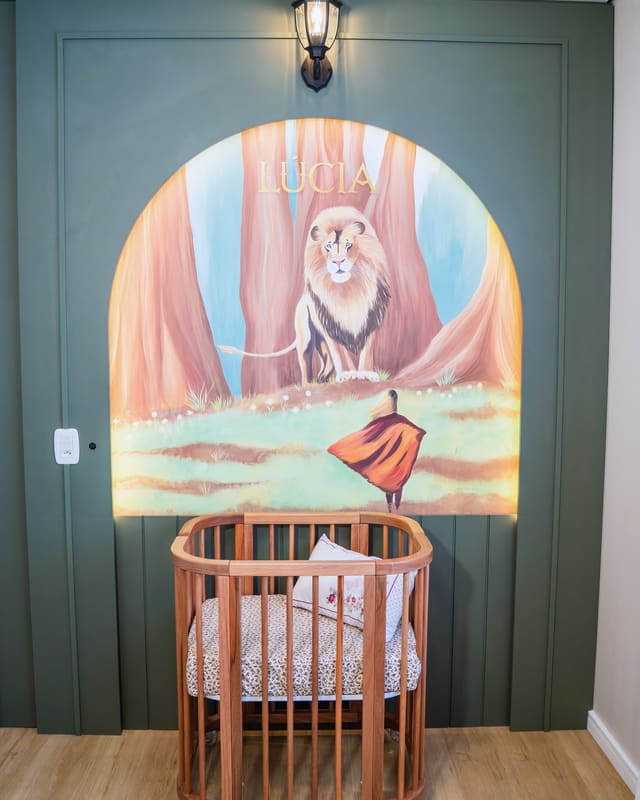 Quarto de bebê com mural pintado à mão, berço oval de madeira e marcenaria verde
