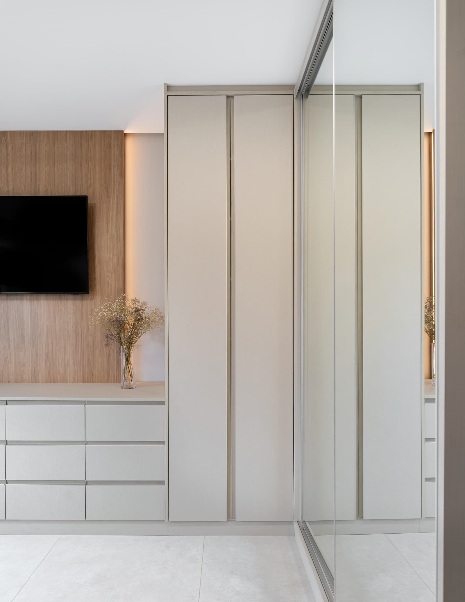 Detalhe da marcenaria do dormitório, com portas de closet e televisão embutida