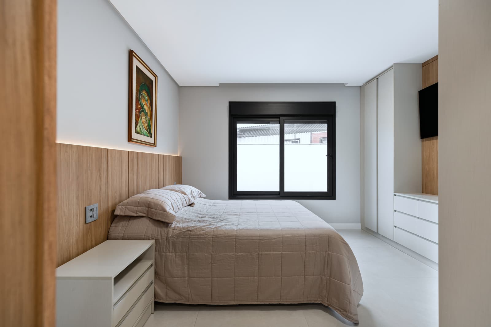 Dormitório com cama, quadro na parede e marcenaria clara
