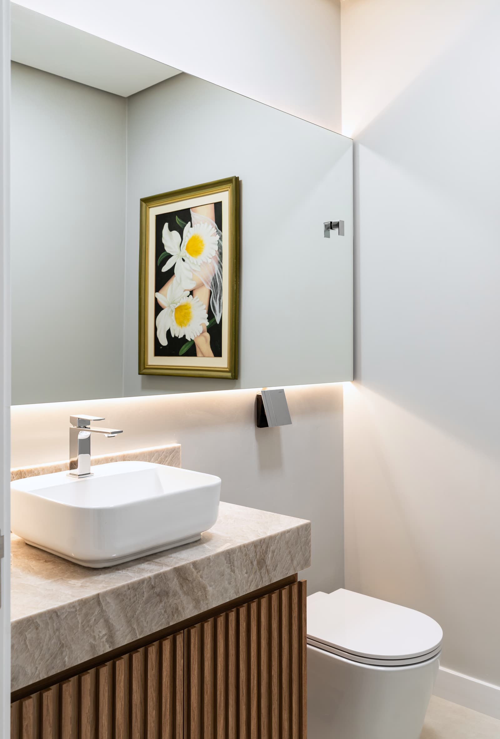 Detalhe de banheiro, com cuba de apoio e quadro de flores na parede