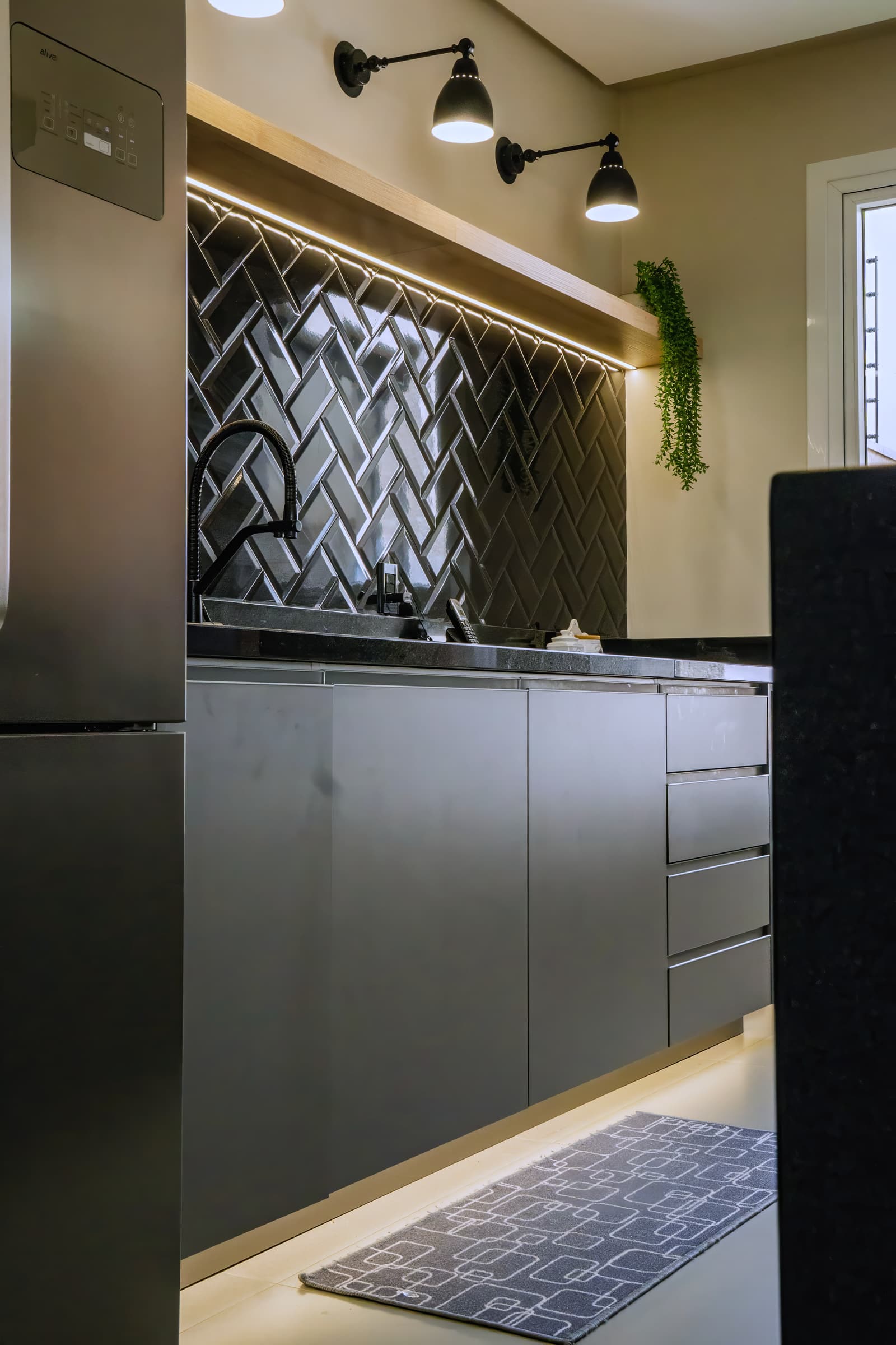 Detalhe do revestimento em espinha de peixe preto atrás da torneira gourmet