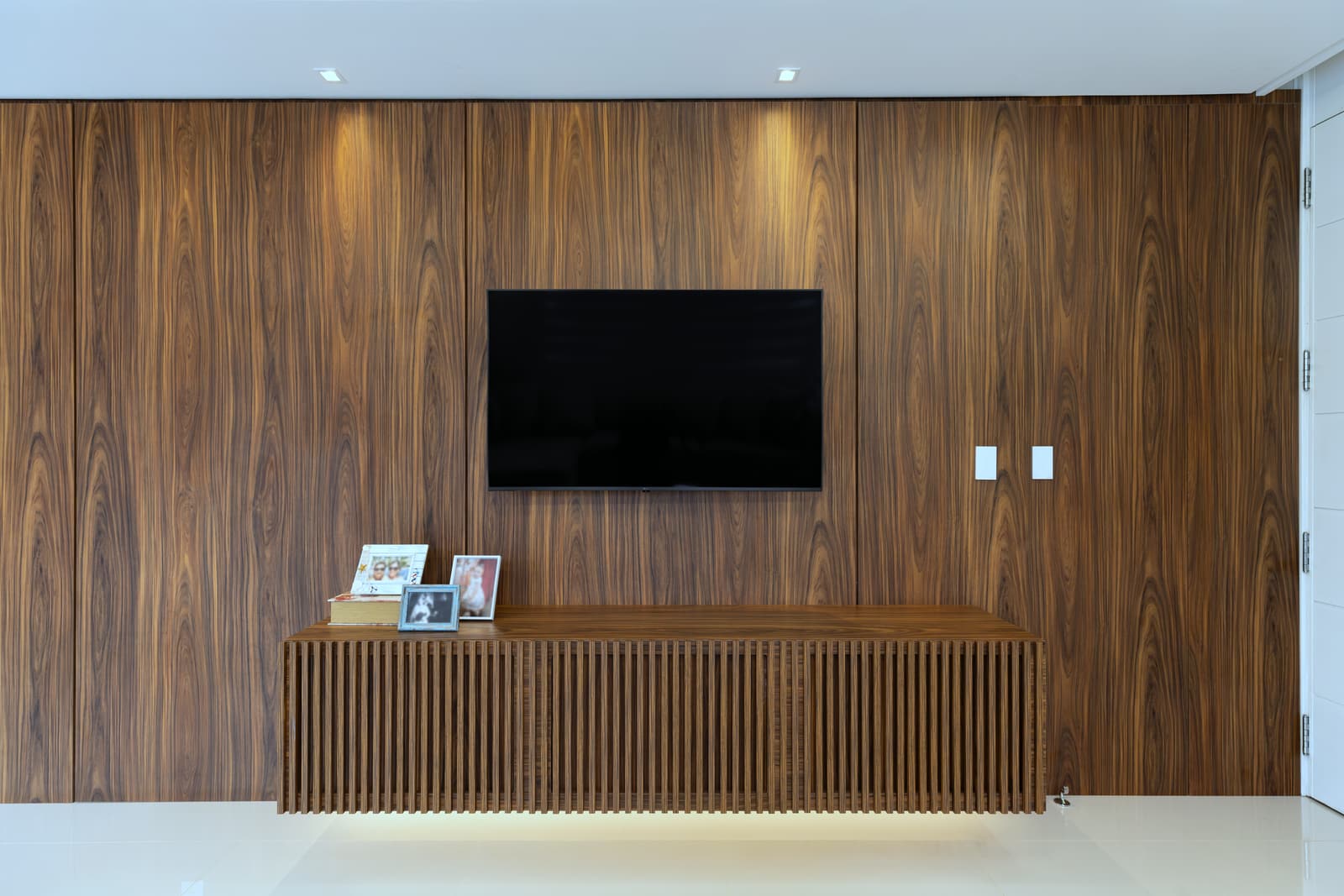 Painel de madeira do piso ao teto na parede da televisão, com base ripada iluminada