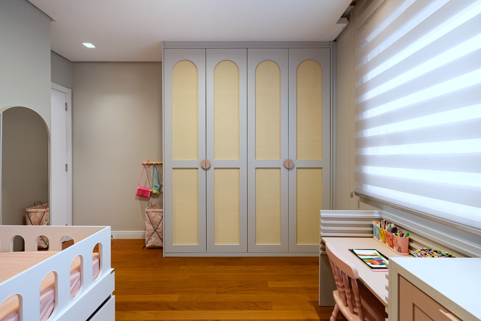Armário do quarto infantil, com portas em arco e marcenaria rosa clara