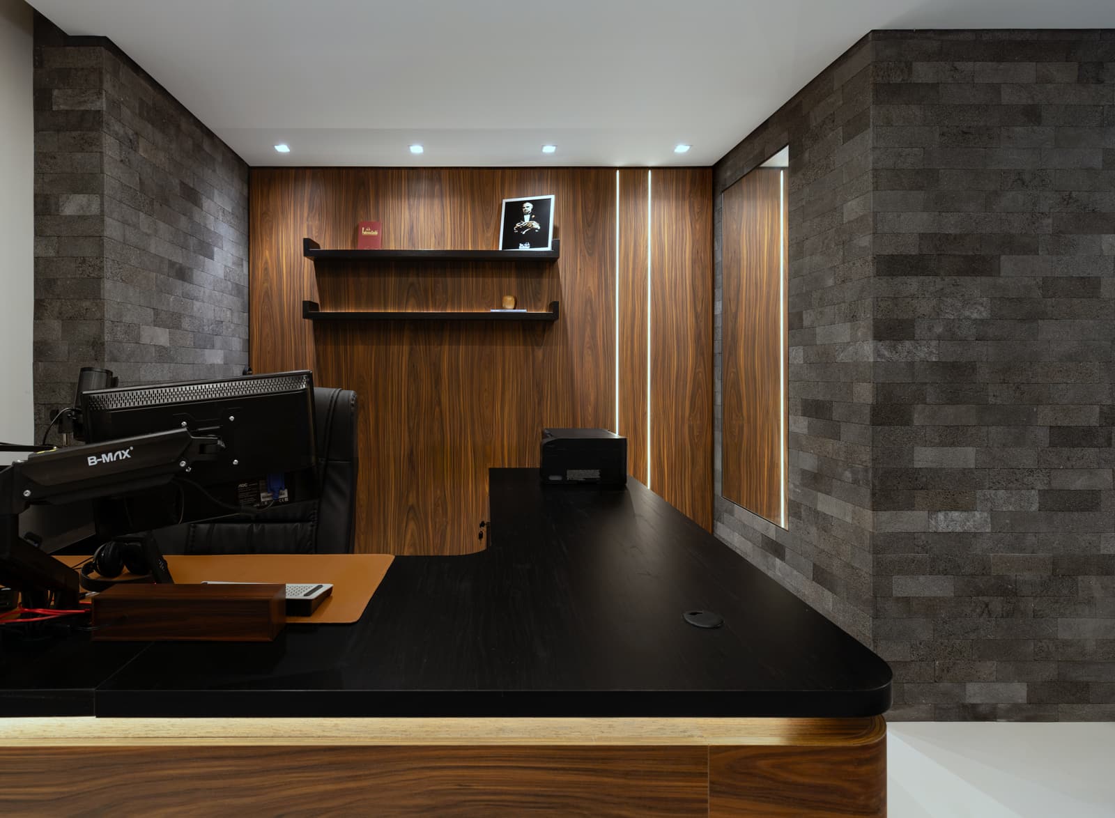 Detalhe da bancada do escritório, com madeira, pedra natural e fita de LED no painel