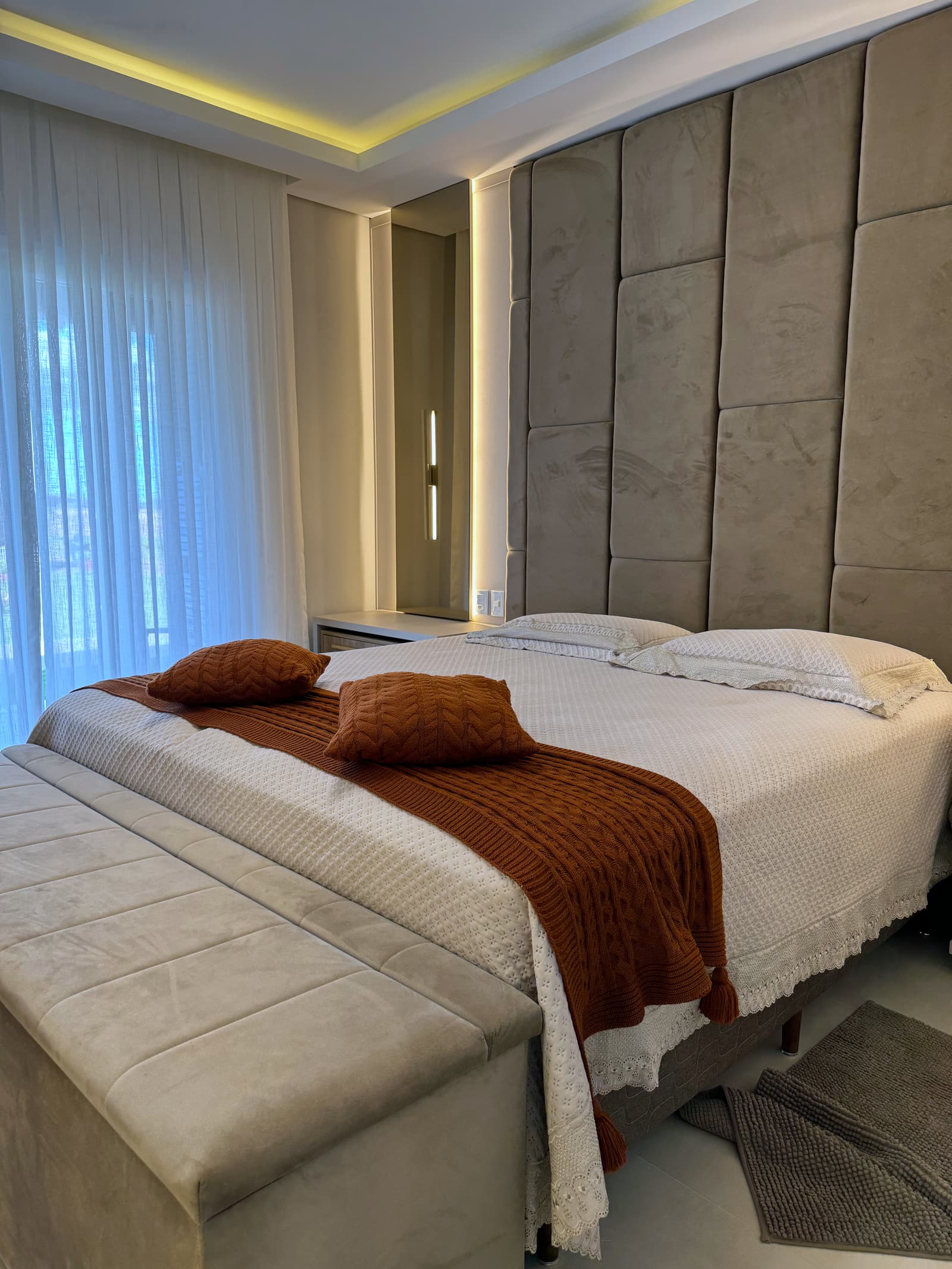 Quarto de casal com cabeceira estofada e manta terracota